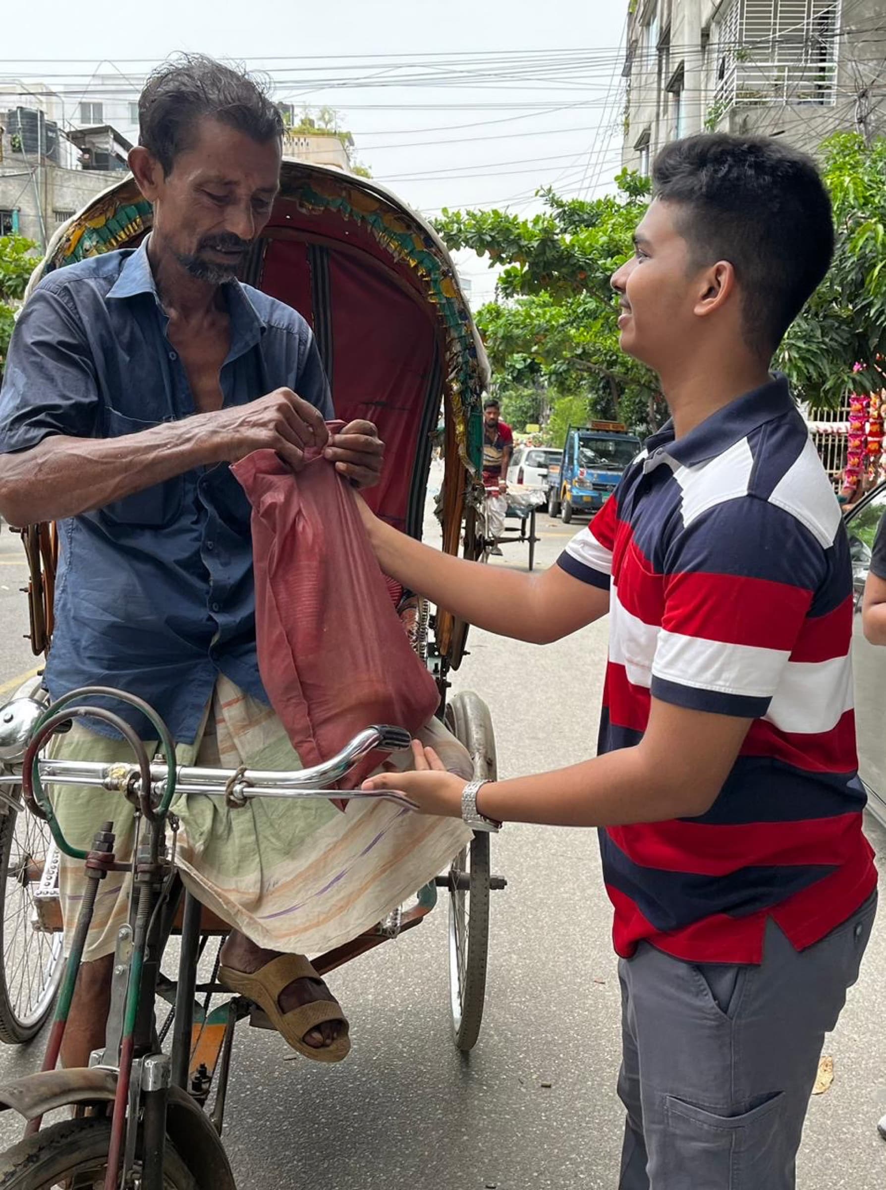 A volunteer handing an Eid food package to a rickshaw puller