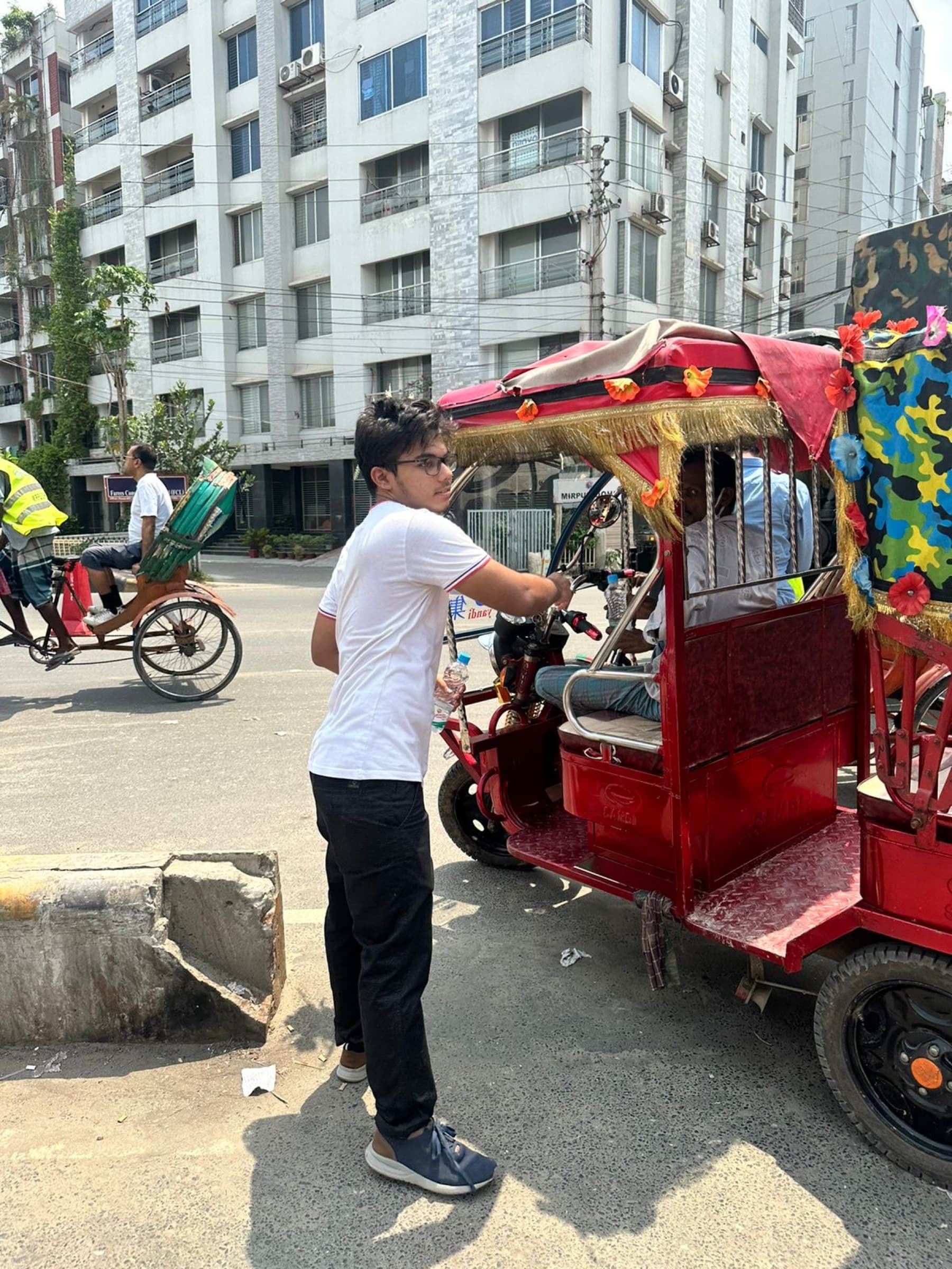 A volunteer delivering water beside a rickshaw in Mirpur