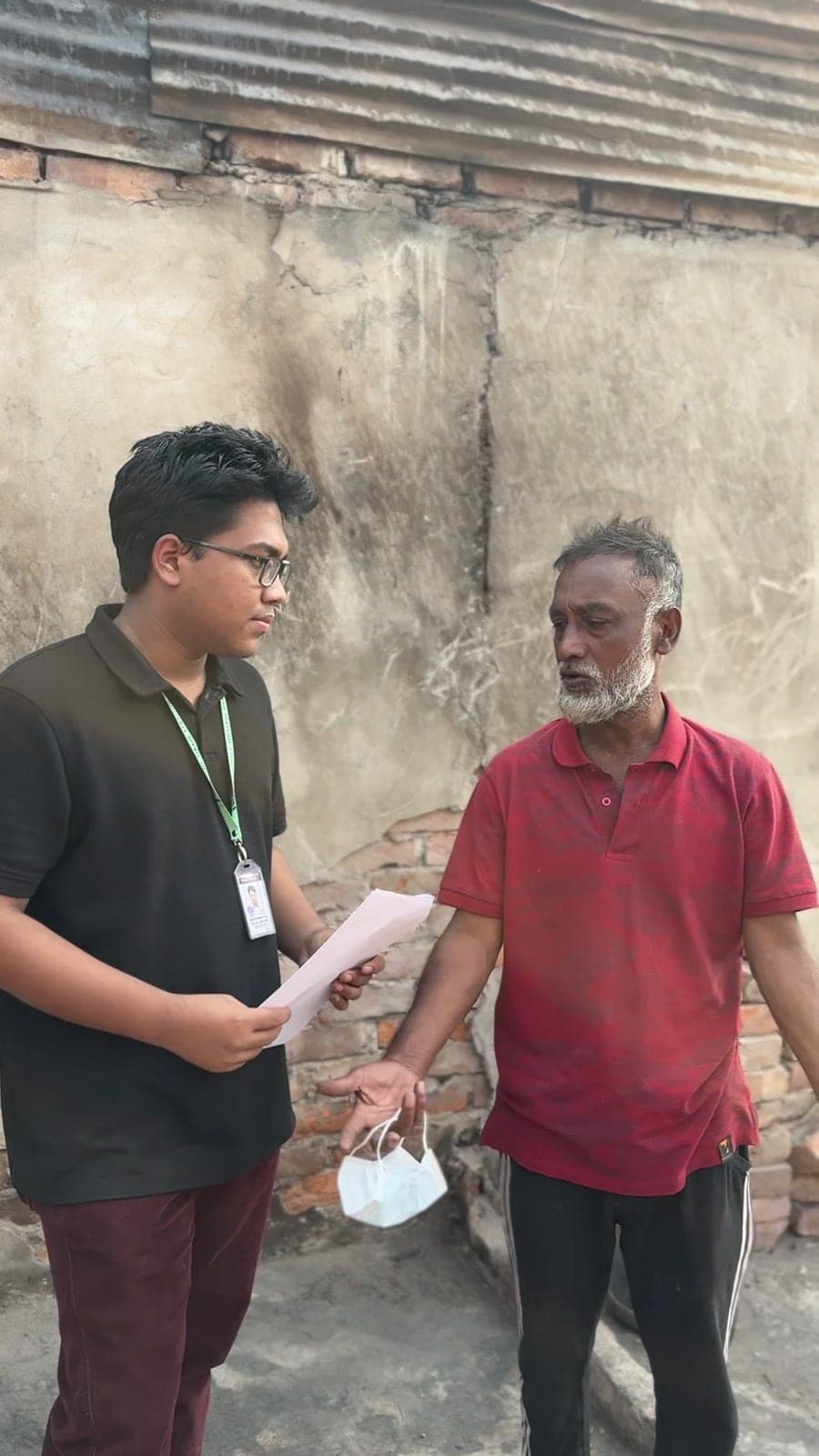 A volunteer speaking with a Korail resident during a field needs assessment