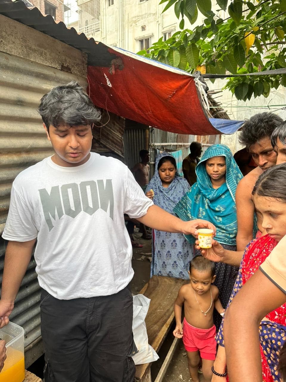 A volunteer handing a drink to a woman in the Mirpur community