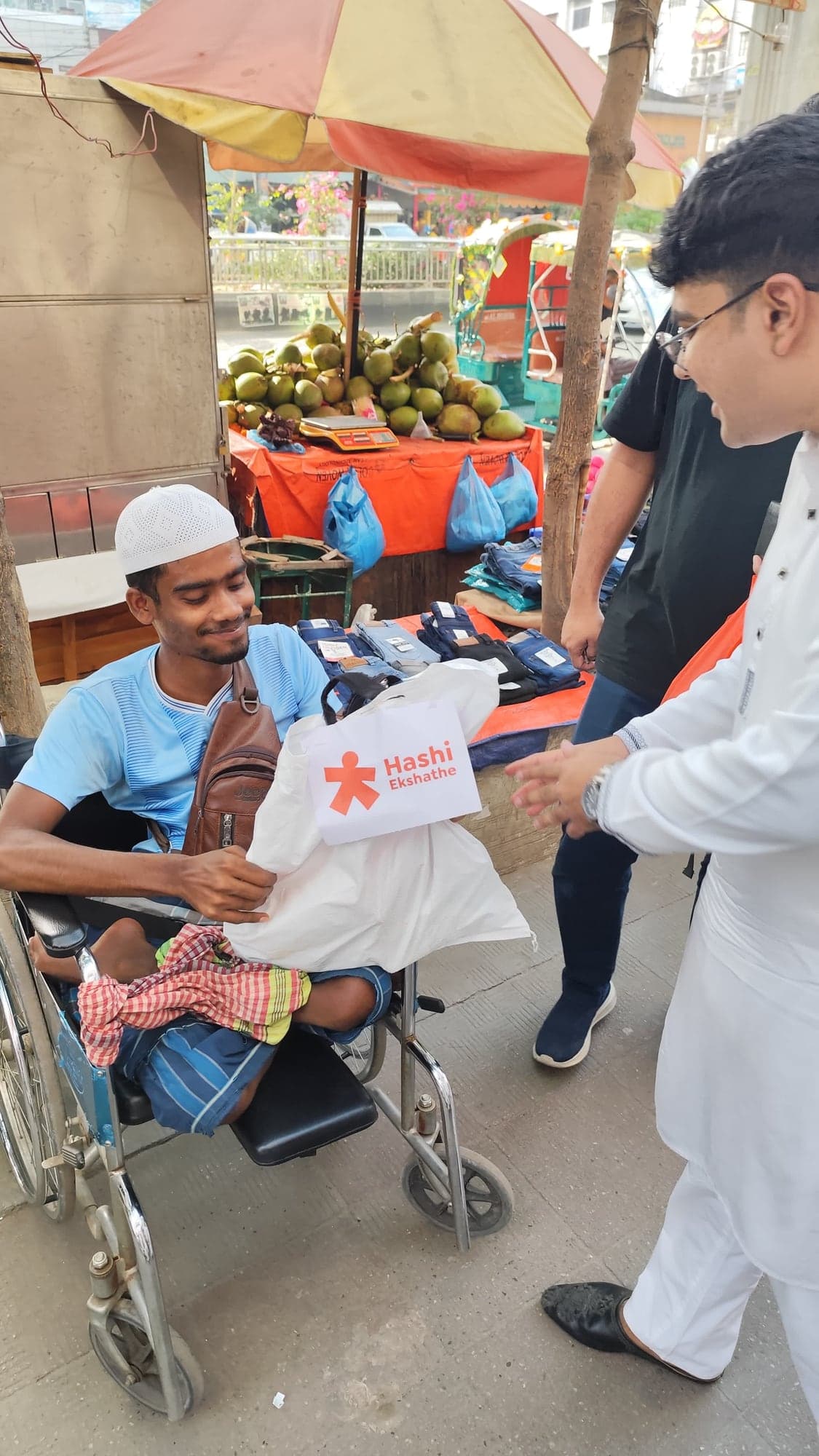 A wheelchair user receiving a Hashi Ekshathe Eid food package