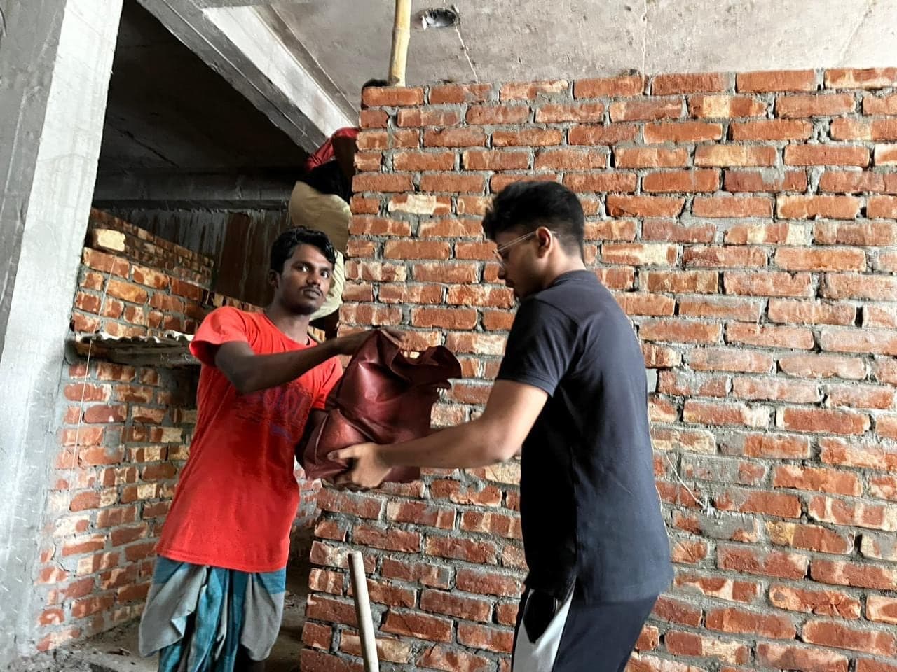 A volunteer handing an Eid food package to a resident at home in Dhaka