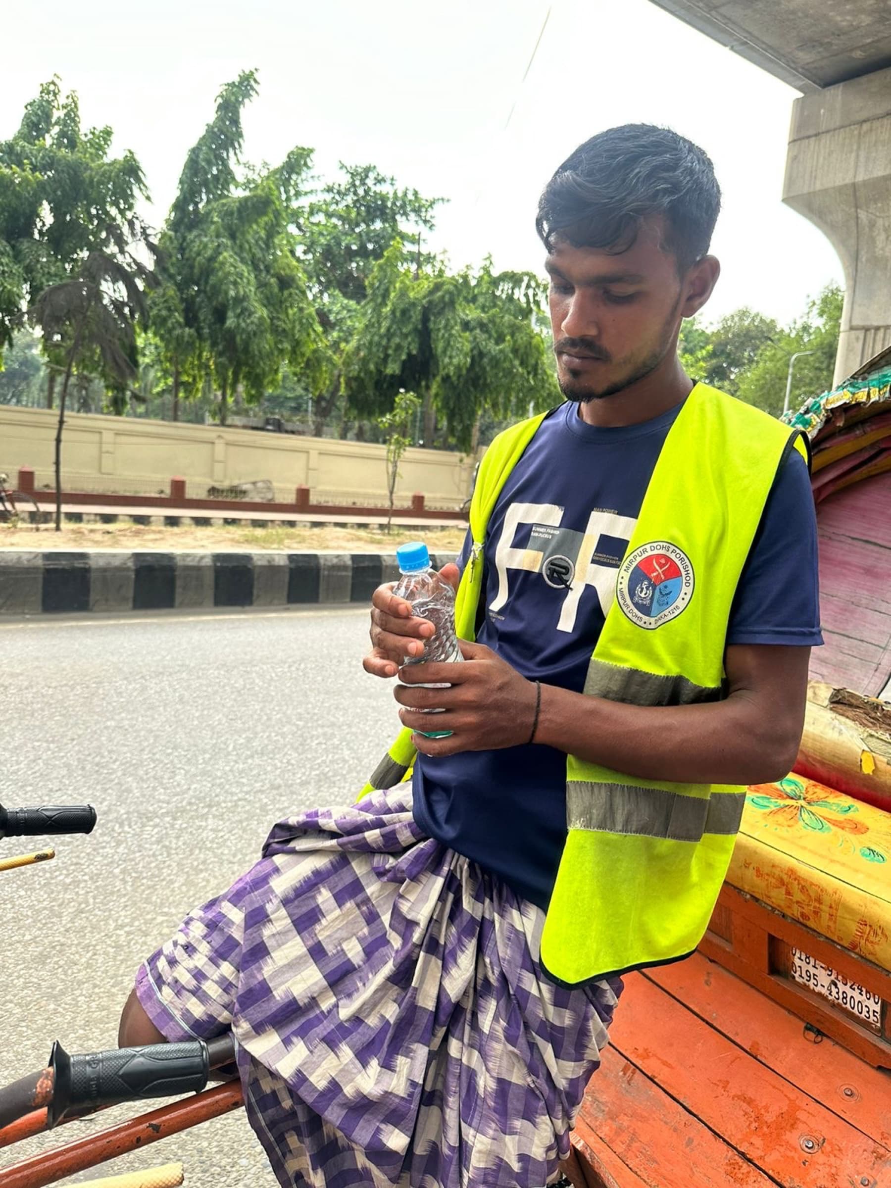 A volunteer offering bottled water to a rickshaw puller during the Dhaka heatwave