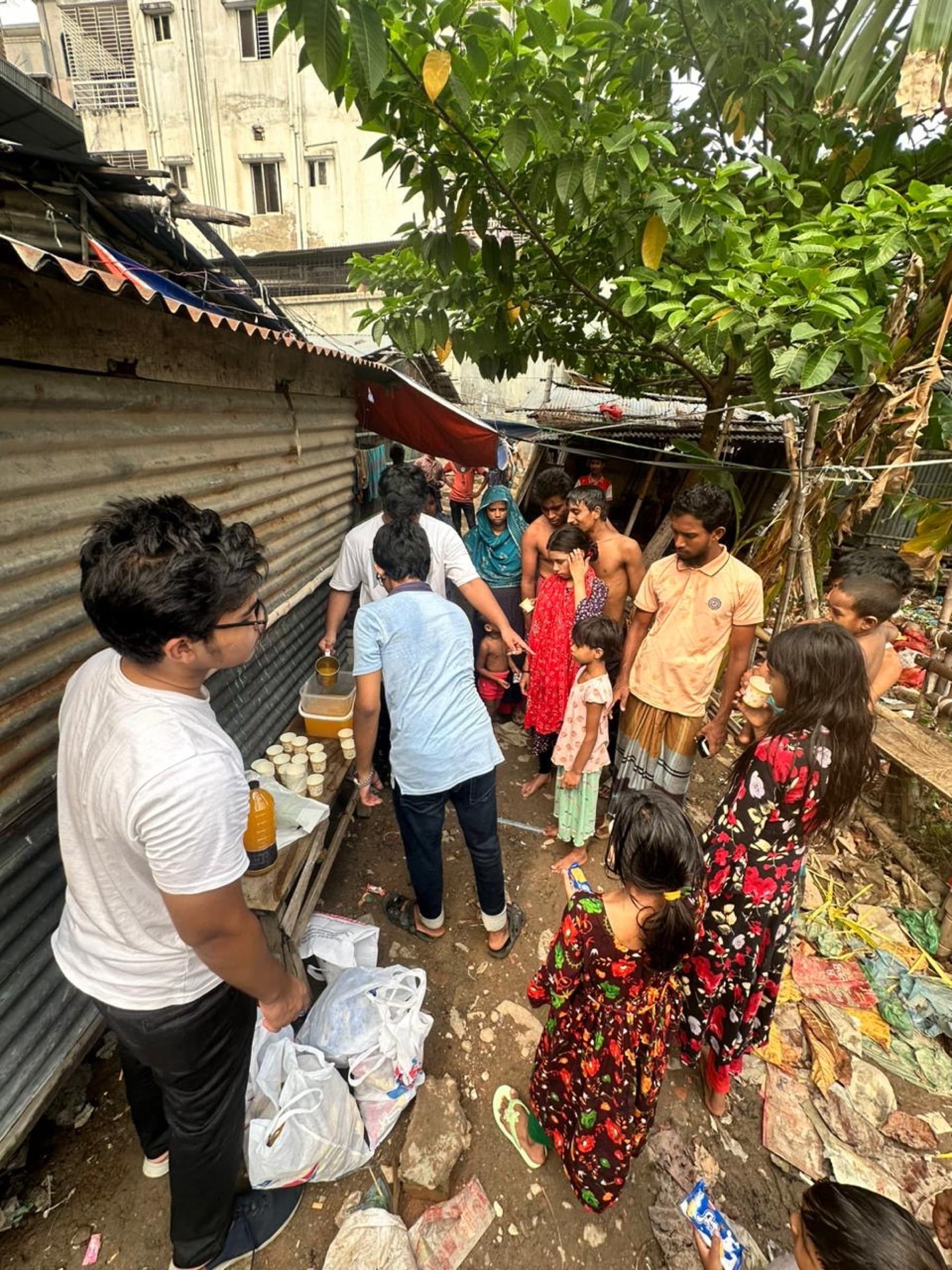Volunteers serving community members beside homes in Mirpur