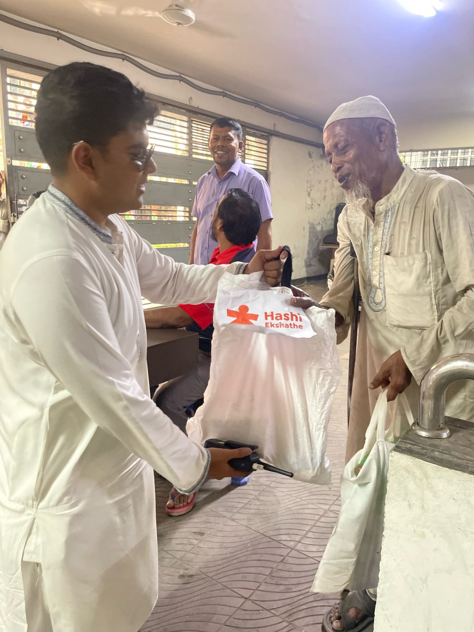 A volunteer delivering a Ramadan food package to an older resident in Dhaka